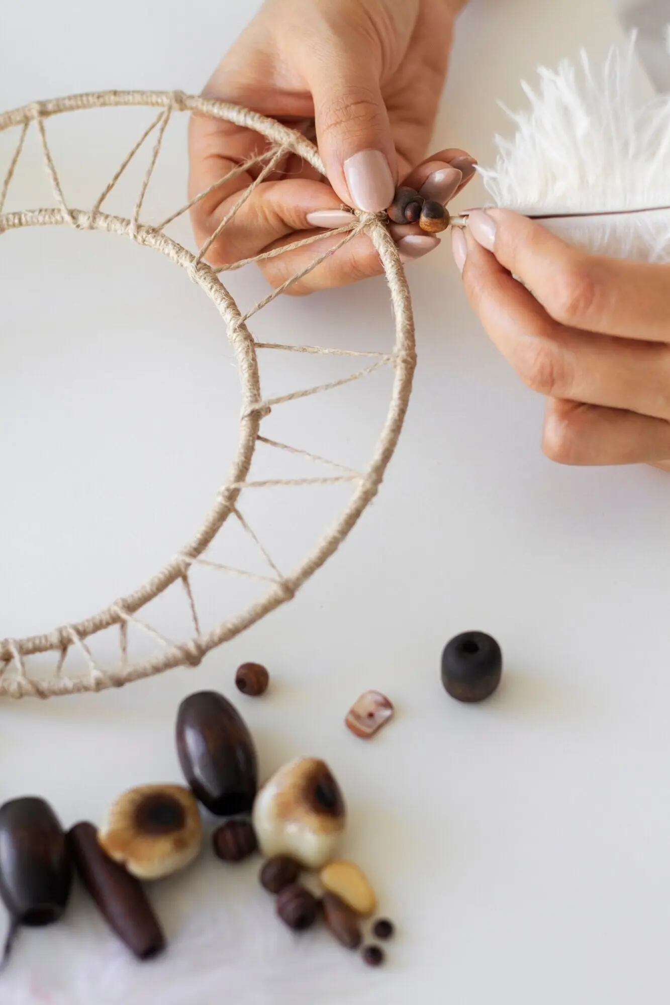 Nahaufnahme einer Person, die an einem Traumfänger arbeitet.